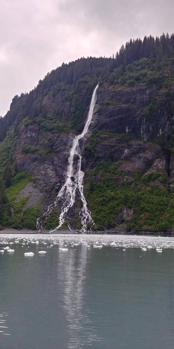An unnamed waterfall caused by glacier melt and run off There is no stream or river feeding the falls and itll disappear once temps cool and ice stops melting Harriman Fjord Prince William Sound Alaska 