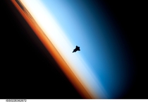  - Endeavour in silhouette against earth The dividing lines between the troposphere orange stratosphere white and mesosphere blue clearly visible