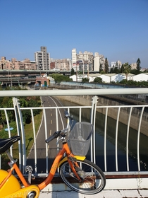  Public bike share bicycle on a path over a flood gate overlooking a canal leading to the Keelong river with walls to withstand flooding another bike path and a two-layer urban freeway in the background Taipei Taiwan