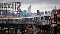  train moving into Queensboro Plaza with the Manhattan skyline in the background 