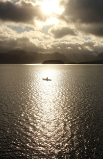 A single canoeist in the sunlight at Derwent Water The Lake District 