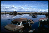 Abandoned automobiles and other debris clutter an acid water and oil filled five acre pond Near Ogden Utah  
