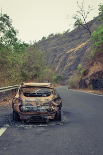 Abandoned burnt car in a mountain pass