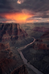 An evening storm cloud dumps rain during sunset on the South Rim of the Grand Canyon in Arizona 