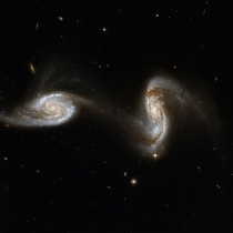 Arp  The galaxies are located very far away about  million light-years and they are in the very early stages of interacting with each other and will eventually merge into a larger galaxy Galaxies of all shapes and sizes are also visible in the background 