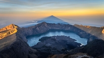At sunrise from the summit of Rinjani Mount Lombok Island Indonesia we can contemplate the triangle-shaped shadow of the volcano over its crater lake 