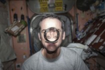 Chris Hadfield watches a water bubble float freely between him and the camera 