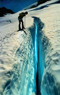 Climber peering down a blue crevasse on Mt Olympus WA 
