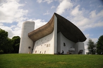 Completed in  Le Corbusiers Ronchamp chapel was built for a Catholic church on a pre-existing pilgrimage site The monumental curved concrete roof is a shell structure supported by columns hidden in the walls A gap underneath allows a sliver of light to fi