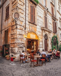 Diners outside a corner restaurant at a cobblestone street in Rome Italy