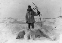 Eskimo polar bear hunter stands over his kill - 