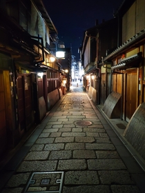 Evening in quiet side street of Kyoto giving way to a busy main street 