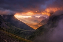 Fiery sunrise light erupts through a break in the clouds over the peaks of Glacier Montana  photo by Nagesh Mahadev