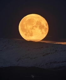 Full Hunters Moon rise above the snow-capped mountains of Senja in Norway