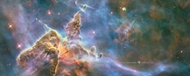 Hubbles th anniversary image shows a mountain of dust and gas rising in the Carina Nebula The top of a three-light-year tall pillar of cool hydrogen is being worn away by the radiation of nearby stars while stars within the pillar unleash jets of gas that