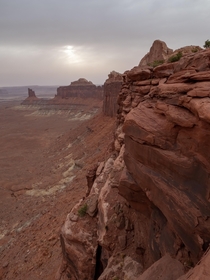 Late in the day sun breaking through the clouds over the canyons edge Moab Utah 