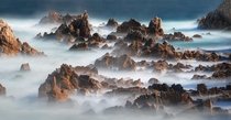 Long exposure of a rocky coast almost looks like an epic range of mountains in fog Haesindang Korea 