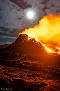 Ongoing eruption in Iceland with full moon above the crater 