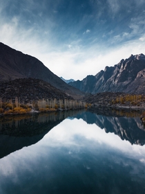 Reflection of rugged mountains and autumn trees in calm Kachura Lake Balistan Pakistan 