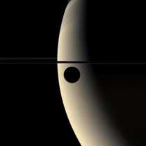 Saturn and its moon Rhea photographed in color a few years ago by the CassiniHuygens probe At right the shadows cast by Saturns rings are clearly visible  photo credit Cassini Imaging Team NASA