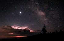 Saturn Jupiter and the Milky Way in the sky and a thunderstorm on the distant horizon seen atop Dolly Sods West Virginia