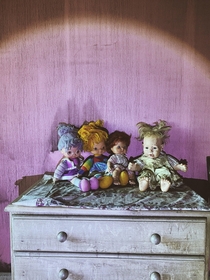 Some dolls watching over a girls abandoned bedroom 