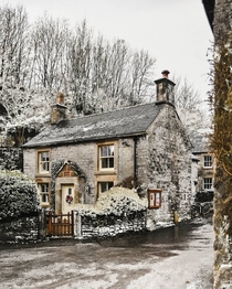 Stone cottage in snowy Milldale Peak District Derbyshire England