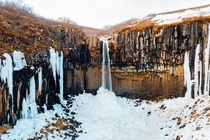 Svartifoss Waterfall flowing into snow mound during winter in Vatnajkull National Park Iceland 