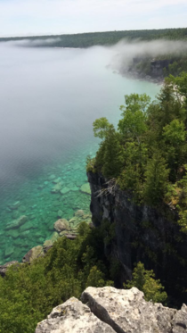 The fog moves off the escarpment revealing the turquoise water and white rocks below A reminder that Ontario is beautiful too Bruce Peninsula National Park 