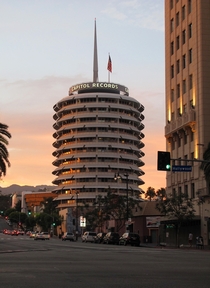 The iconic Capitol Records Building at sunset viewed from the corner of Hollywood amp Vine Completed in  its an excellent example of the futuristic Googie style of architecture 