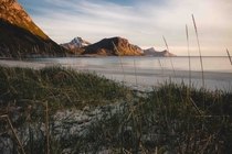 The midnight sun coloring the mountains and white sands of Haukland Beach in Norways Lofoten Islands 