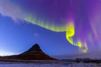 The sun hadnt set fully yet they were so bright they were dancing over this triangular mountain Kirkjufell Iceland 