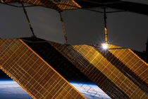 The sun shines through the solar panels of the ISS 